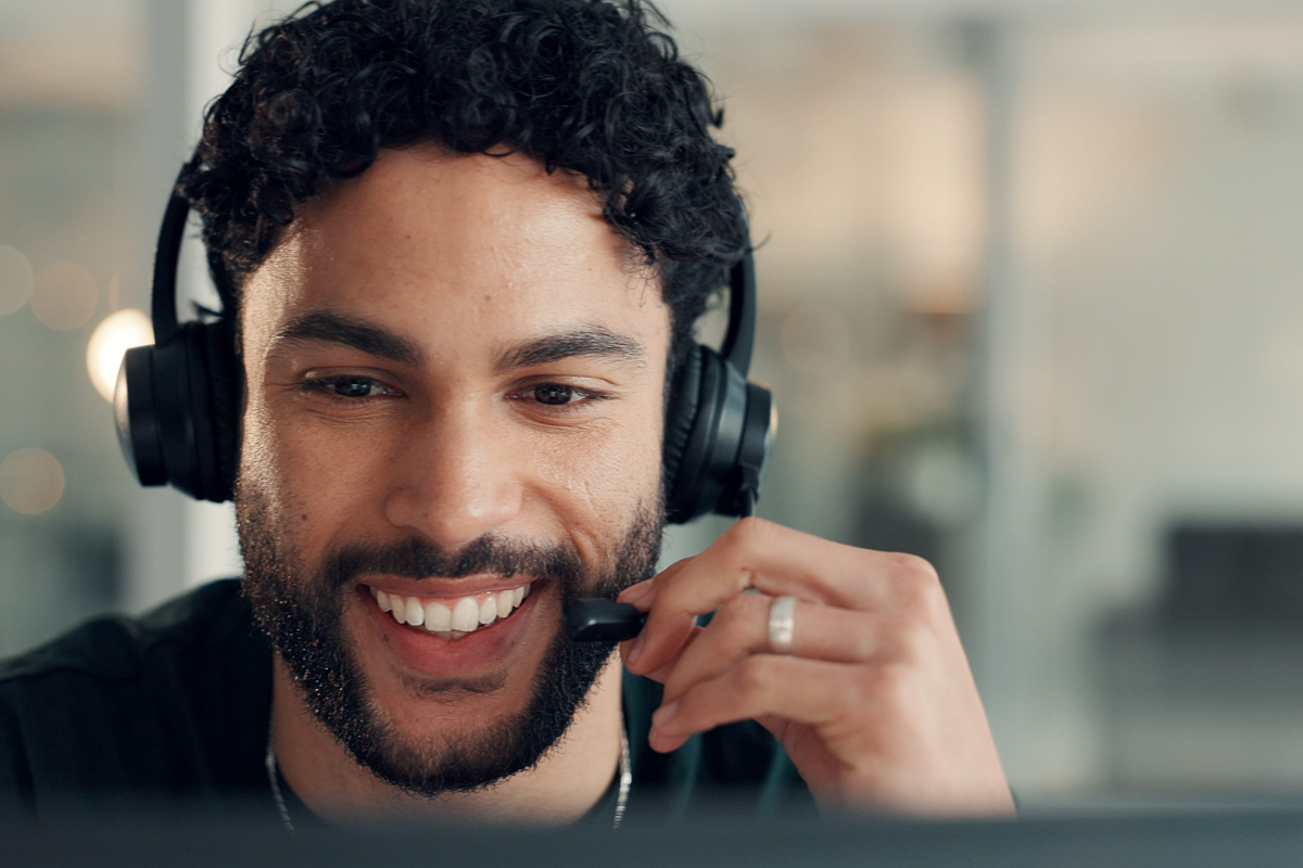 Smiling call center agent adjusting a headset while handling a customer call.