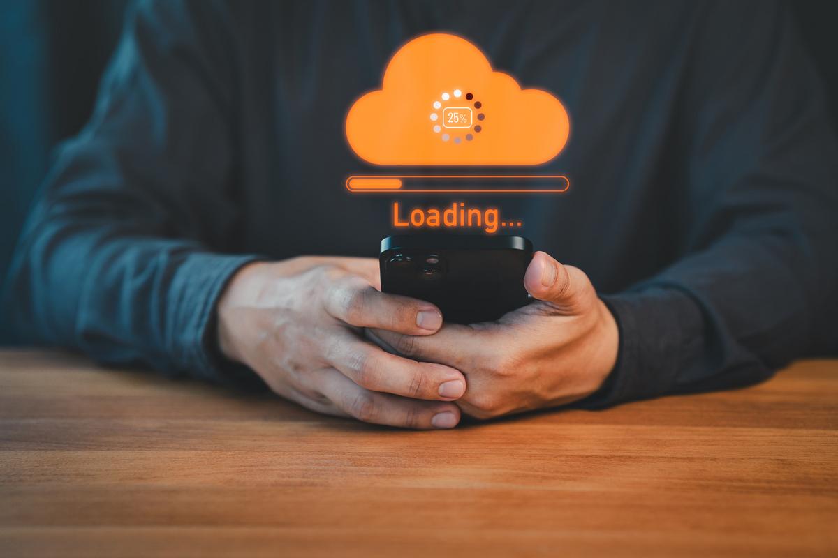 Man using mobile phone with digital cloud hovering above it