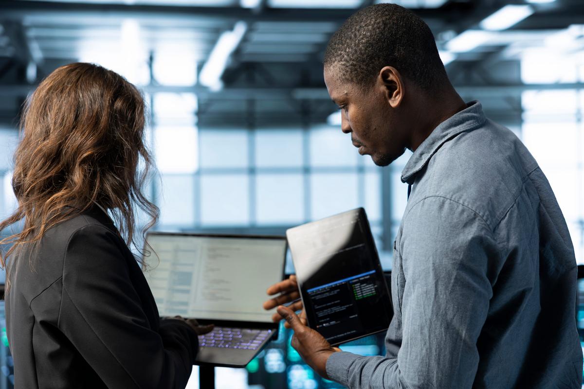 Two colleagues looking at each other's laptops.