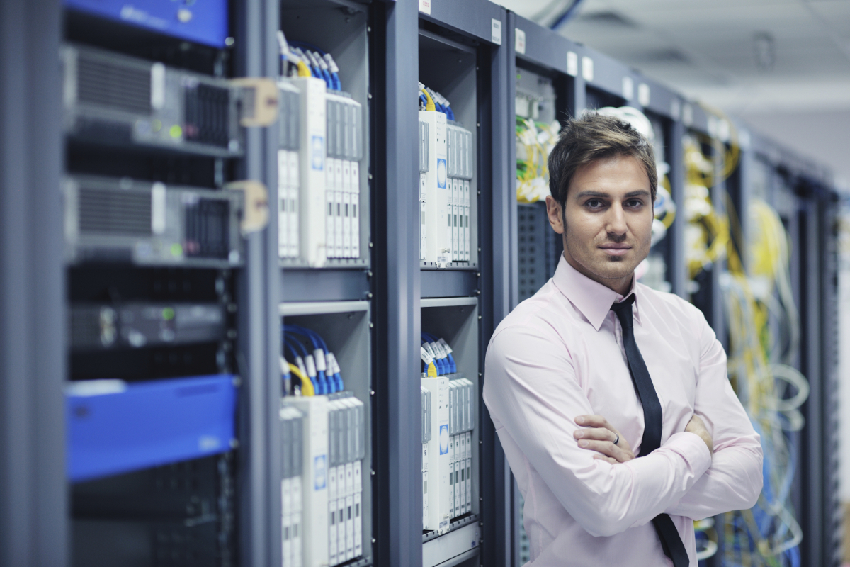 An employee standing infront of network and server hardware