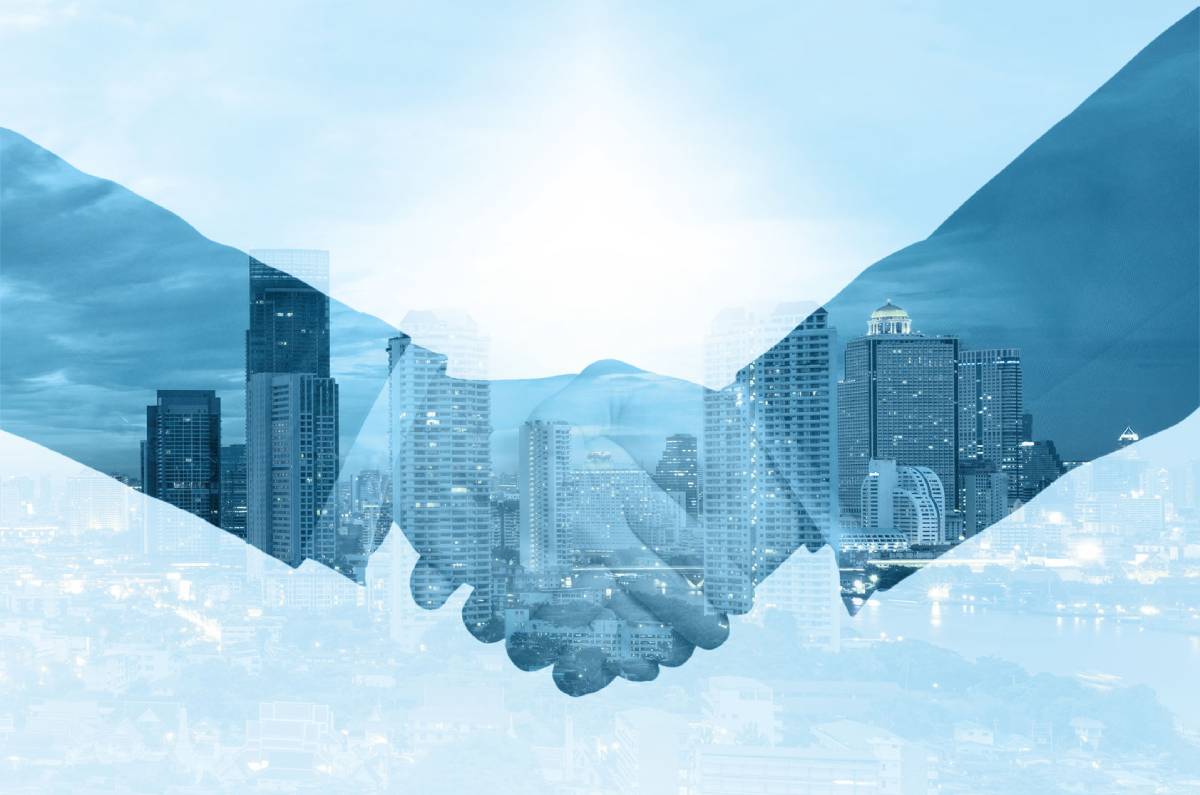 Close up of a handshake inter-posed over a cityskyline and tinted blue and white.