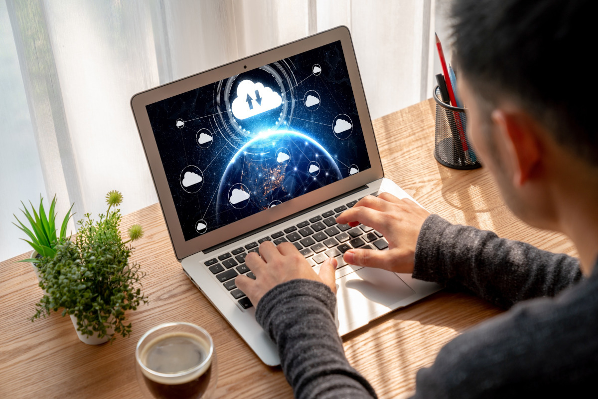 A man working on a computer with cloud icons on the screen