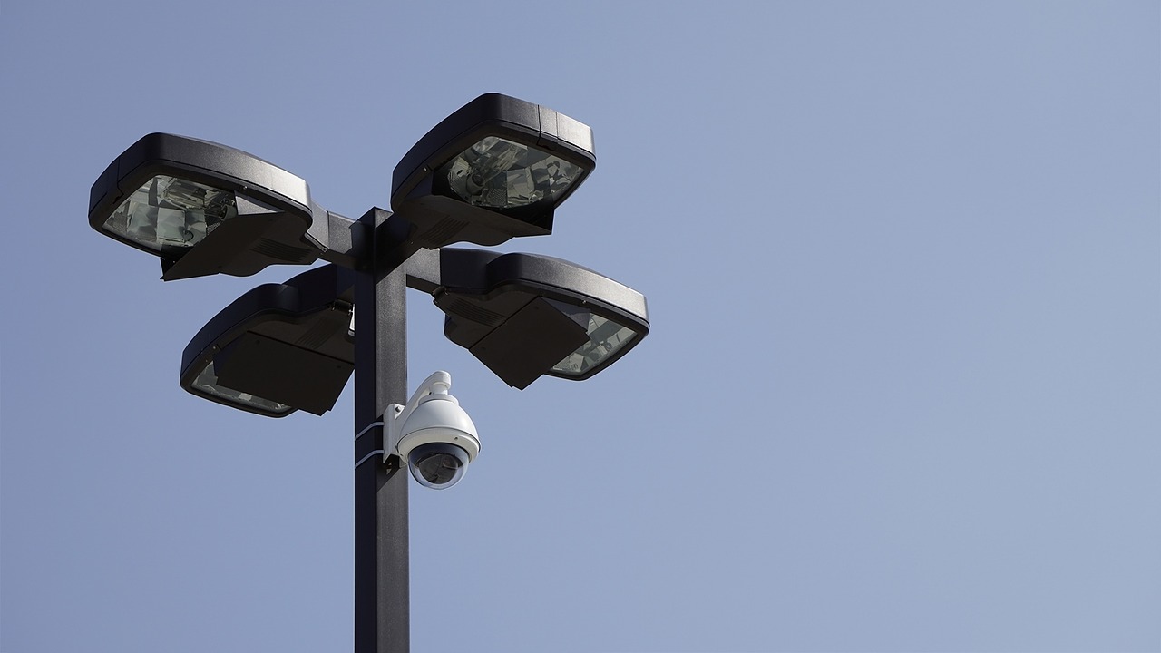 A surveillance camera installed onto a lamp post with four lights.